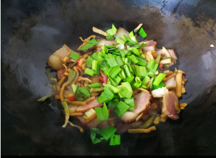 Stir fry the dried radish until it is a little brown. Add the small red pepper, and stir fry it for ten seconds, add green pepper, shredded ginger, and bacon, continue to stir fry, and then add some soy sauce, soy sauce, and garlic sprouts, and stir fry it for two to three minutes.