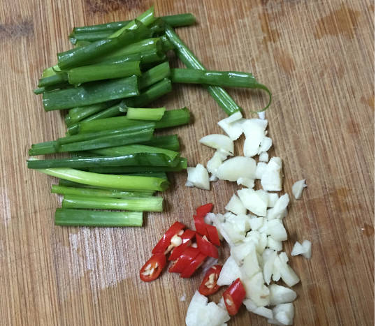 Wash and cut the scallion into sections, chop the garlic, and cut the millet pepper into circles.