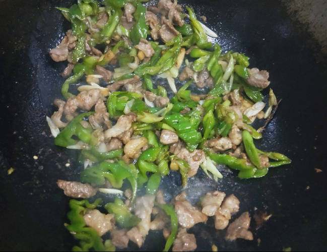 Heat the oil, stir-fry the meat until it is half-cooked, and set aside the hot oil, sauté the scallions, ginger, and garlic until fragrant, then add the chopped peppers and stir-fry.