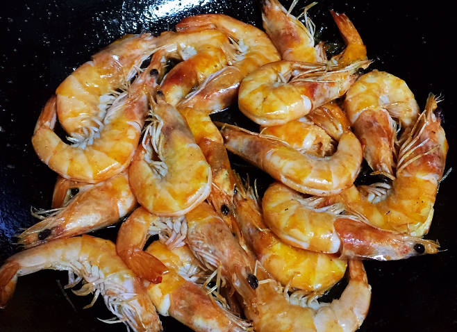 Pour more vegetable oil into the frying pan, put in the prawns, and fry until they turn red and brown on both sides, set aside.